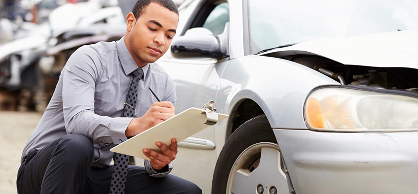 An insurance agent inspecting the damages to a car