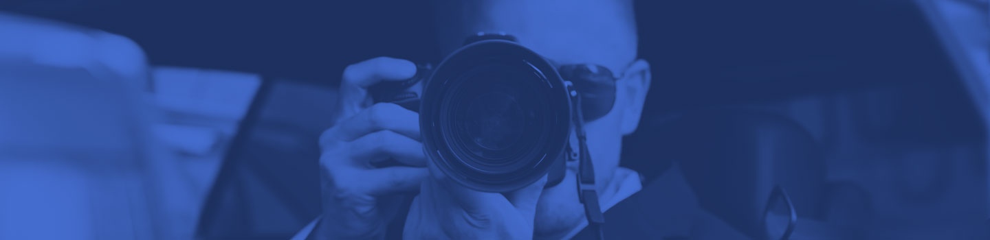 A covert man taking photographs from the inside of a car