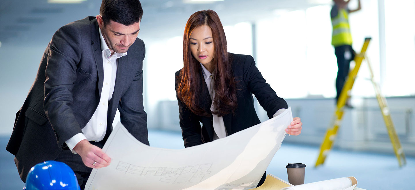 A business owner and architect looking over floor plans for their new building